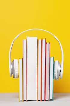 A stack of upright books with headphones placed over them, symbolizing audiobooks.