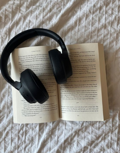 Black headphones placed on an open book, representing audiobook listening.
