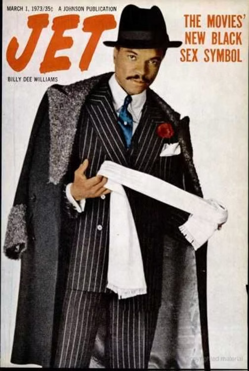 Jet Magazine: Man in pinstripe suit and fedora holds a scarf, draped coat, red rose on lapel. Text: "JET," "The Movies’ New Black Sex Symbol." Retro vibe.