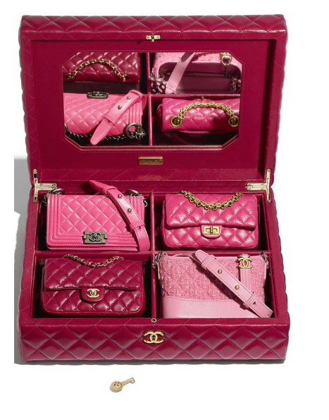 Open pink Chanel case displaying multiple miniature pink handbags arranged inside.