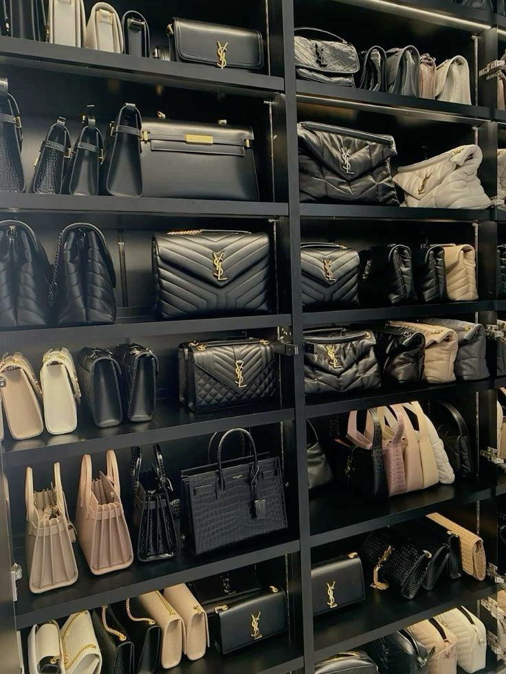 A closet shelf filled with Saint Laurent handbags in black, beige, and neutral tones. Different styles including quilted leather, top-handle, and crossbody bags are neatly displayed.